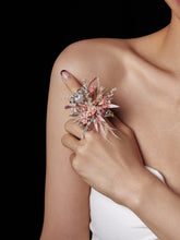 A person with bare shoulders gently holds the CAMELLIA Confession Valentine’s Day Flower Ring, a handcrafted floral arrangement, embodying elegance against a black backdrop.